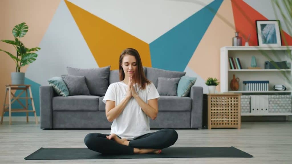 A woman calmly meditating in a living room
