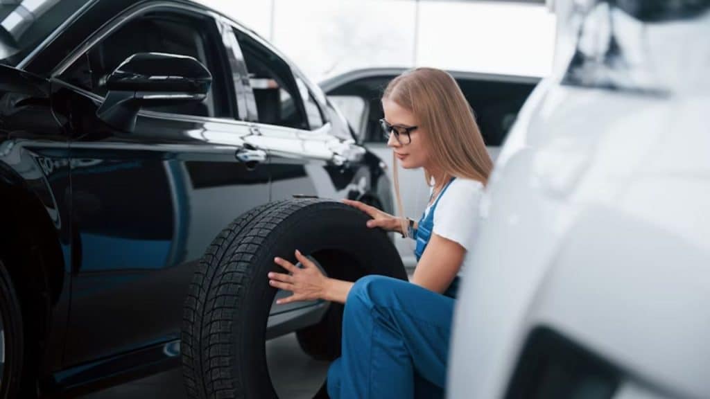 A woman smiling while fixing a flat tire