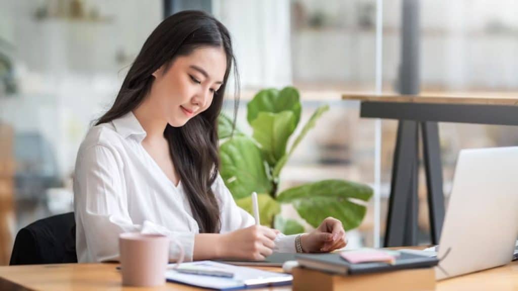 A woman journaling with a cup of tea nearby