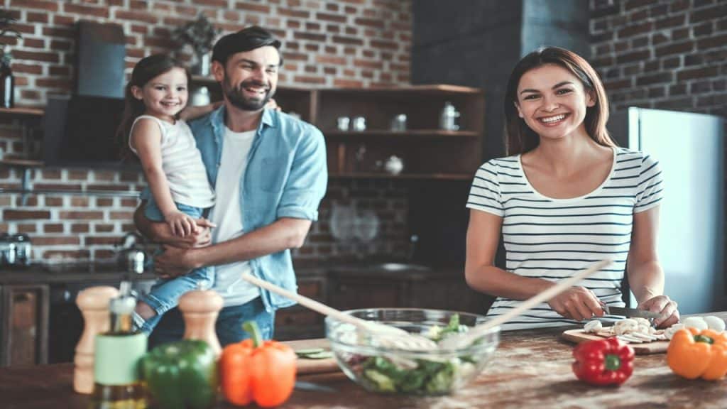 A small family in the kitchen together.