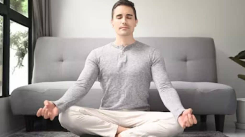 A man meditating on a yoga mat in his living room