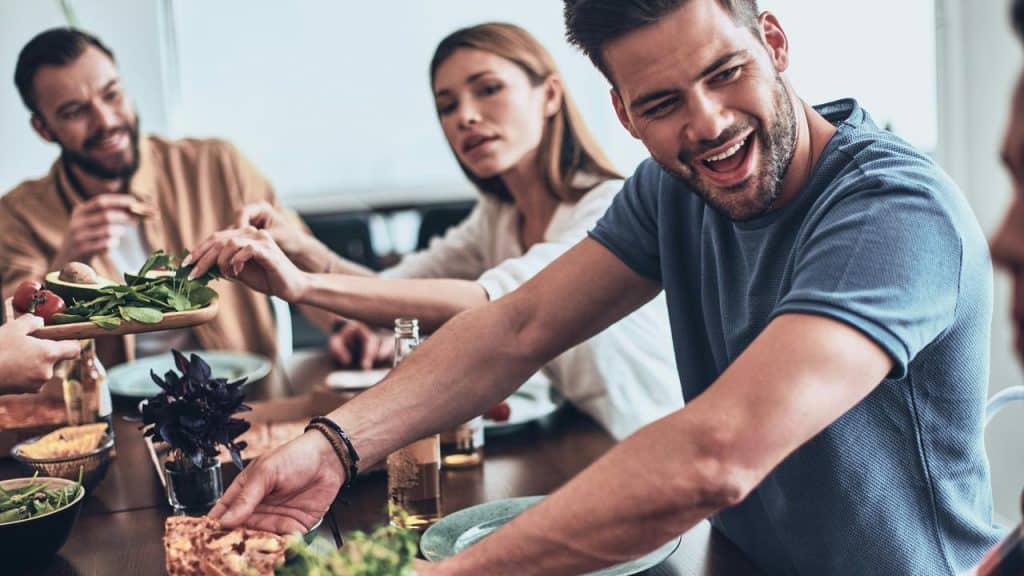 A group of friends sit at a table sharing food and laughing together.