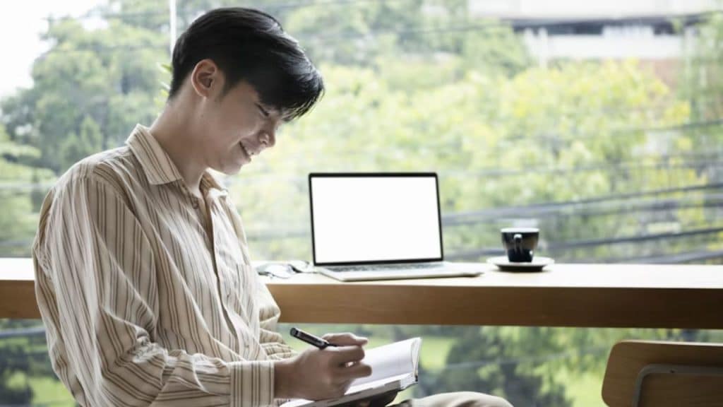 A man journaling at a desk with a cup of tea