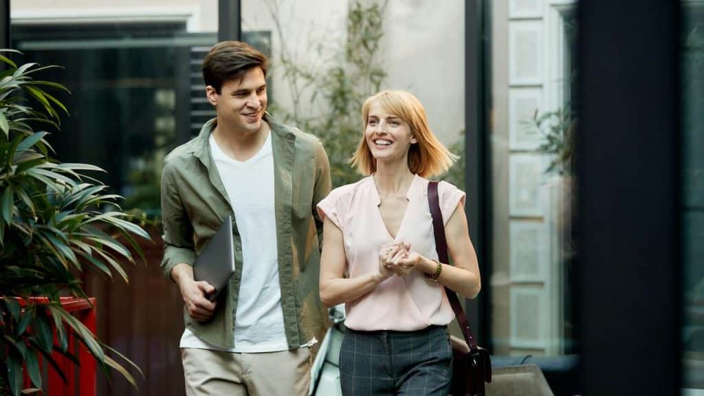 A man and woman walking together outdoors, smiling and talking.