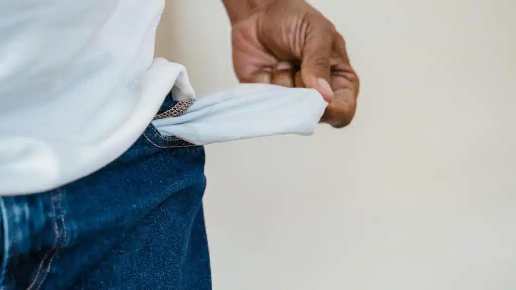 A person pulling out an empty pocket from their jeans.