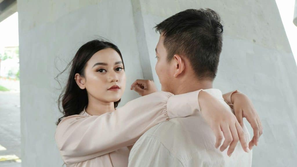 A woman with dark hair embraces a man and looks intently at the camera.