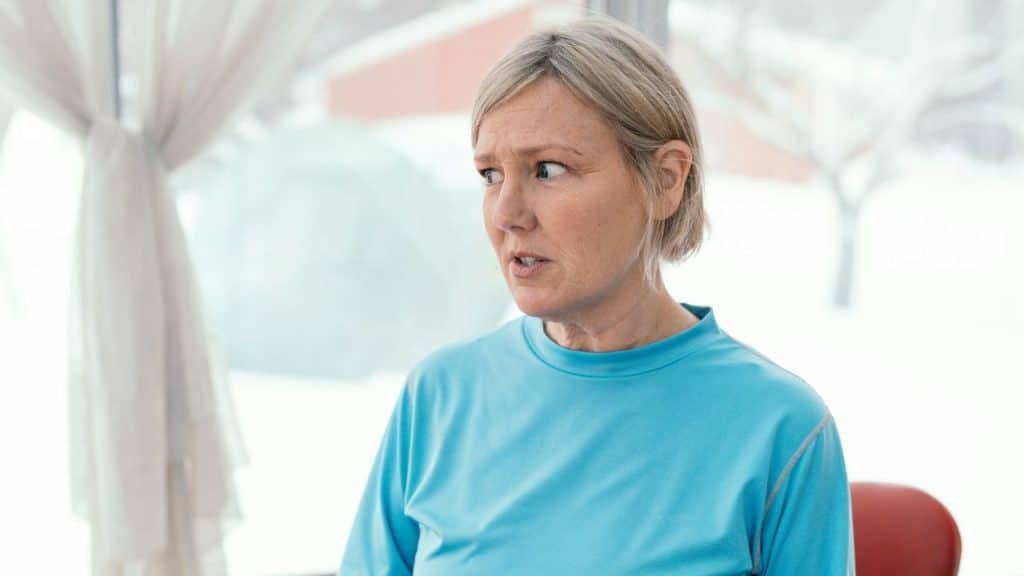 A woman with short blonde hair looks off to the side with a shocked or worried expression.