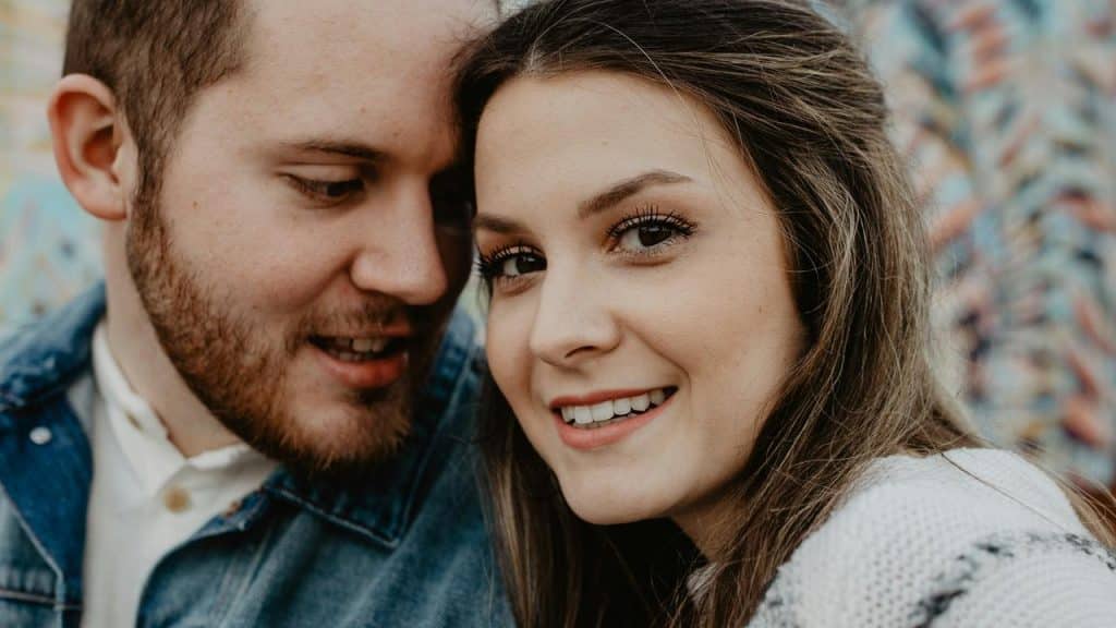 A smiling woman with a man leaning close beside her.