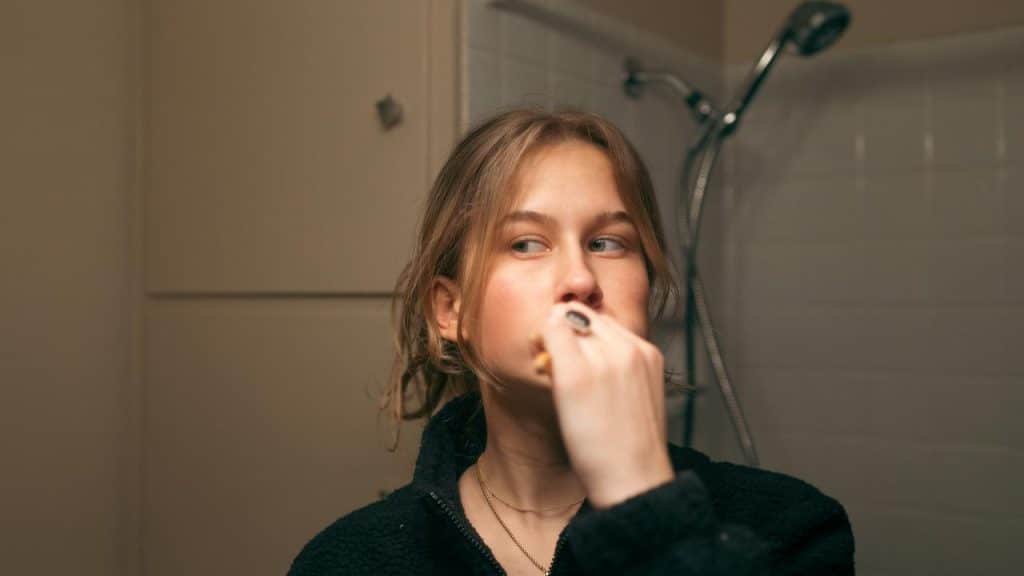 A young woman brushing her teeth in a bathroom.