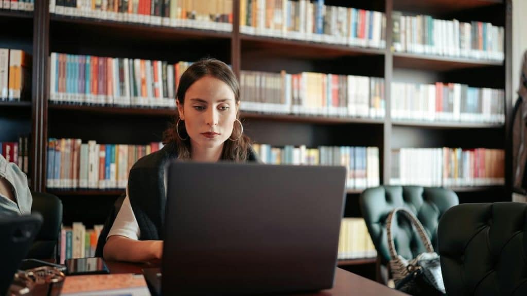 A woman working on a laptop in a library.