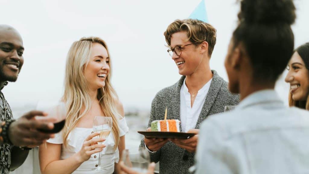 A group of friends smiling and chatting at an outdoor birthday party.