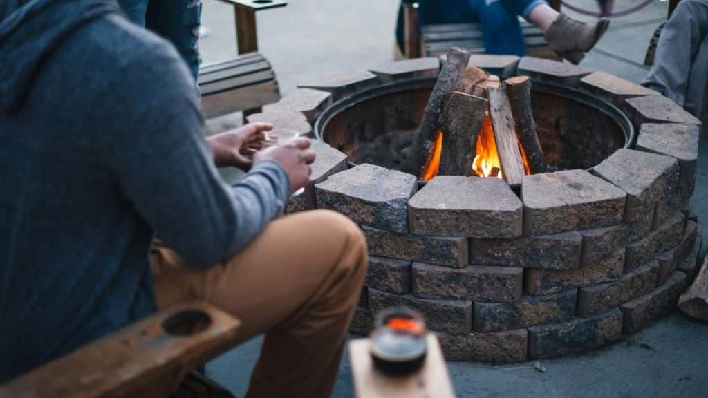 A group of people sitting around a fire pit outdoors.