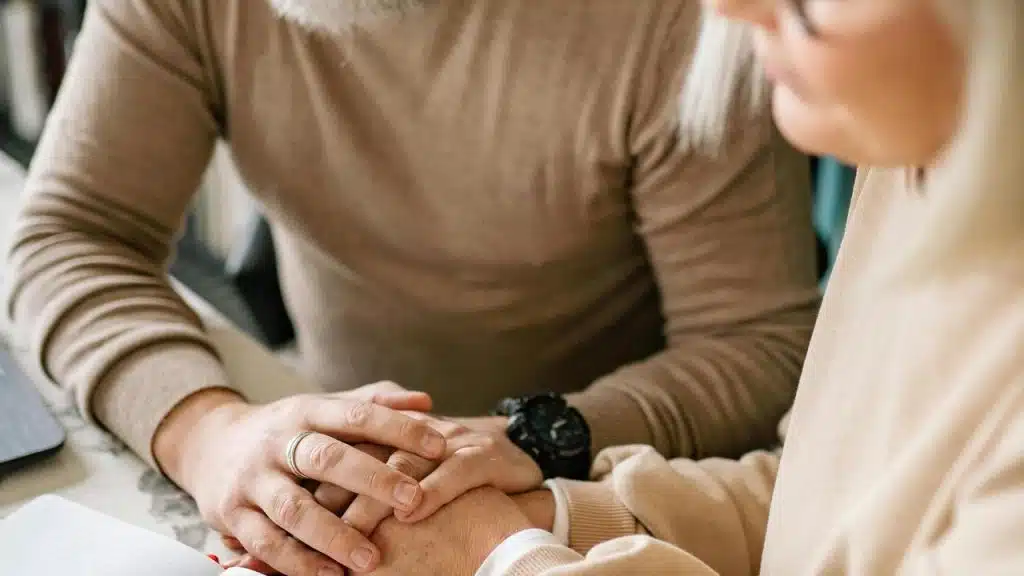 A senior couple holding hands at a table.