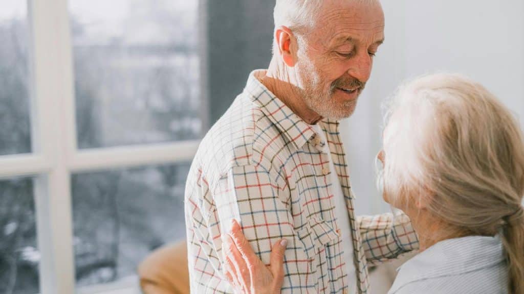 A senior couple smiling and dancing together at home.