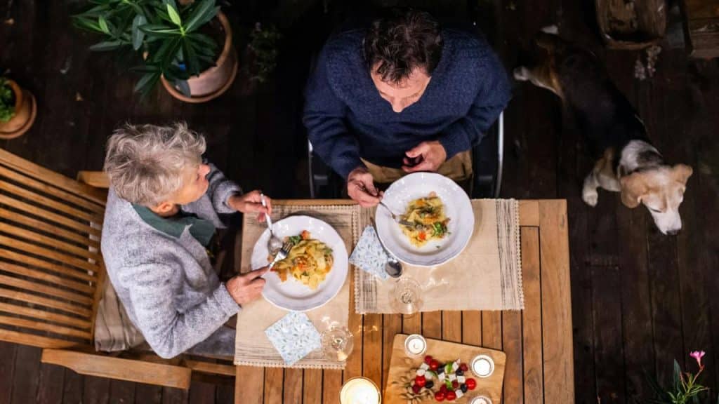 An older couple having dinner together at a wooden table.