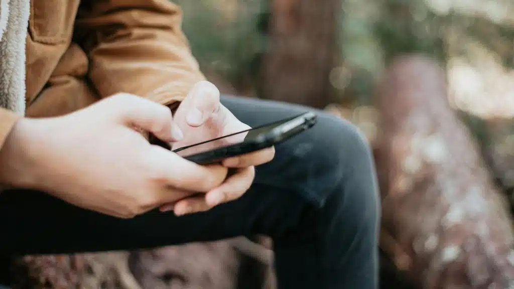 A close-up of someone outdoors using a smartphone.