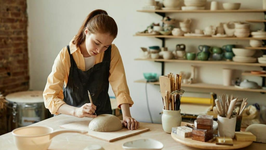 A woman works on a clay sculpture in a pottery studio.
