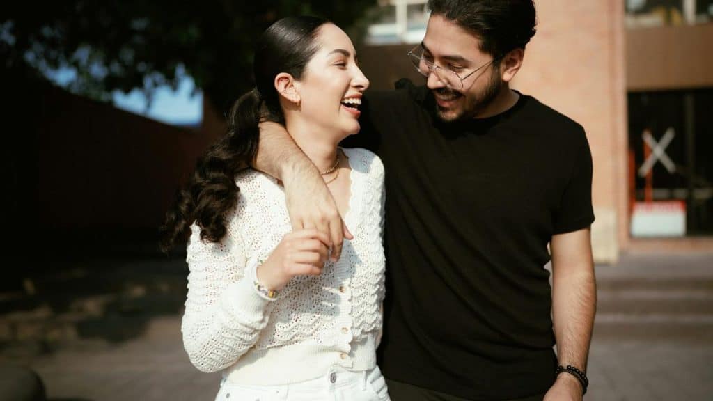 A smiling couple walks together with arms around each other.