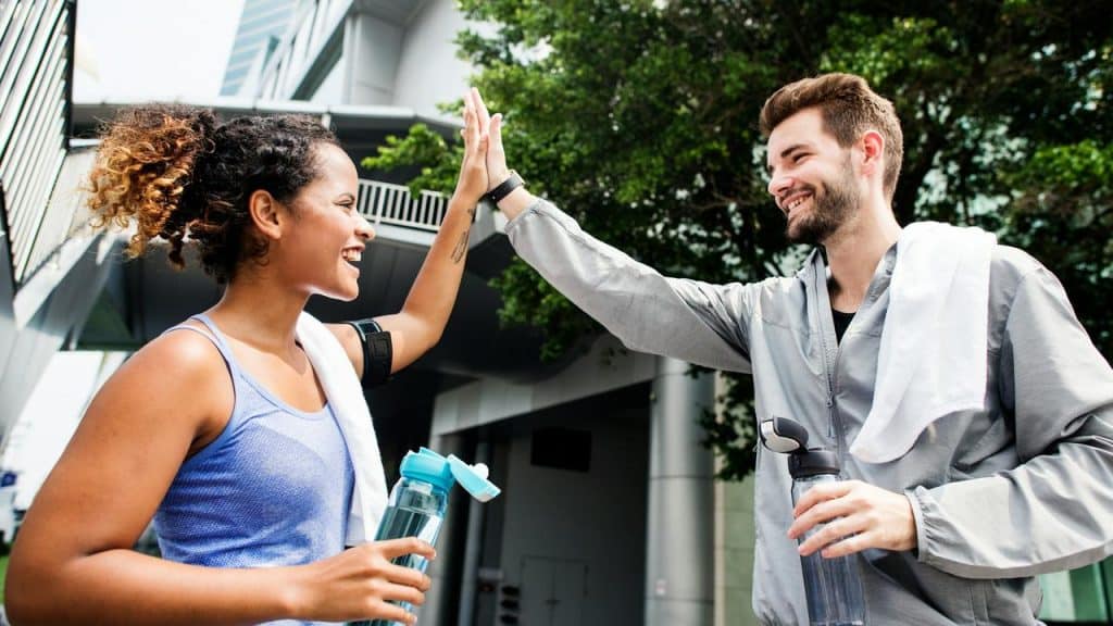 A man and woman high-five after exercising outdoors.