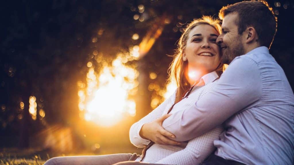 A couple embraces and smiles at sunset.