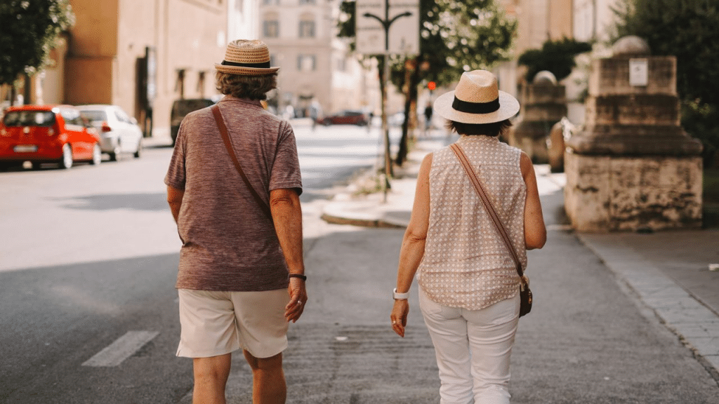 A mature couple walking separately from each other on a street in a European city.