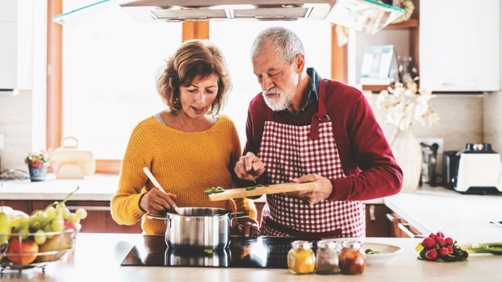 A middle-aged couple in their kitchen cooking a meal together.