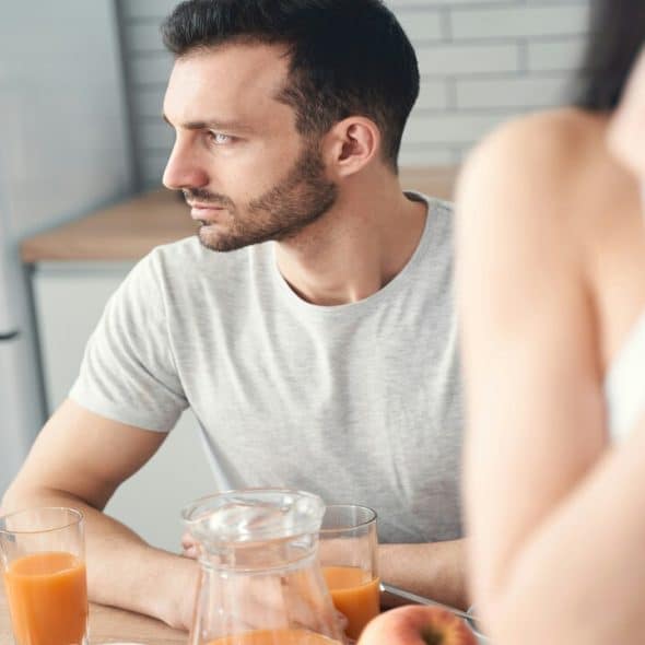 A man looking sad during breakfast with his wife