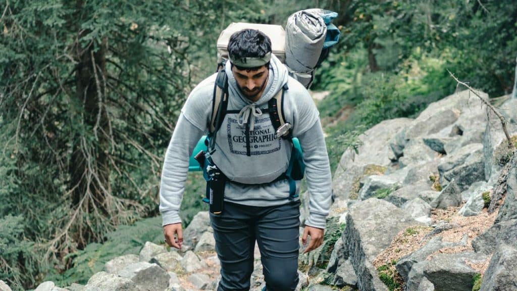 A determined hiker with a large backpack walks up a rocky path.