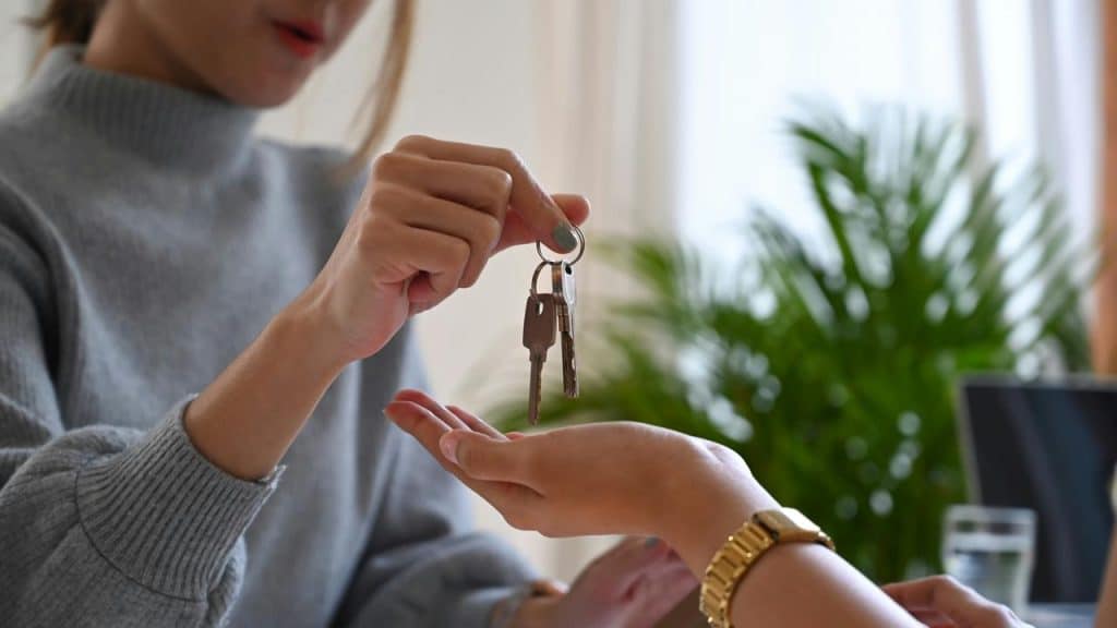 A person handing over house keys to another person.