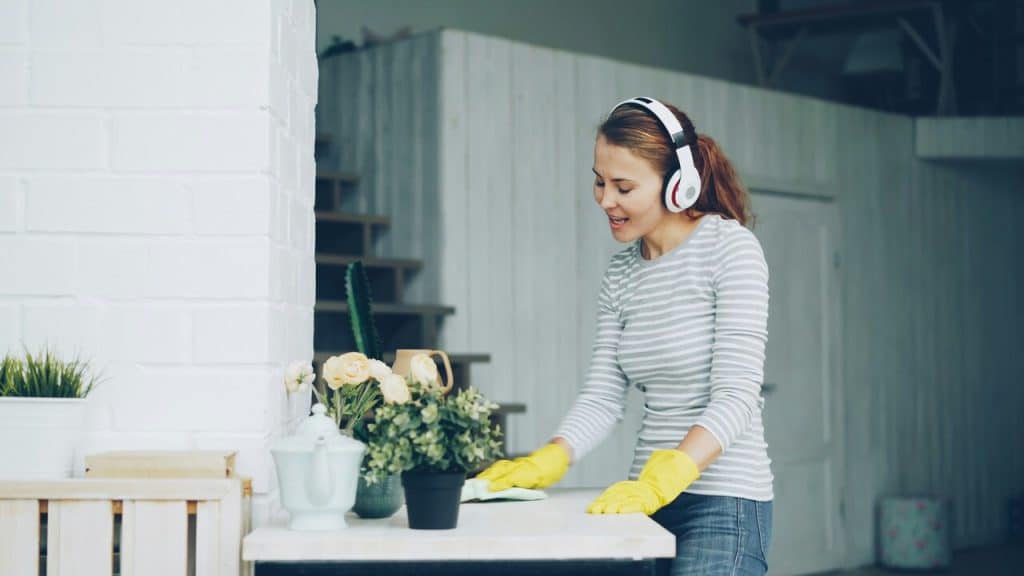 A woman using her headphones while cleaning