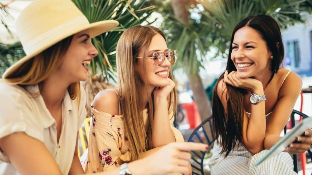 Three women are sitting together at a cafe, smiling and laughing.