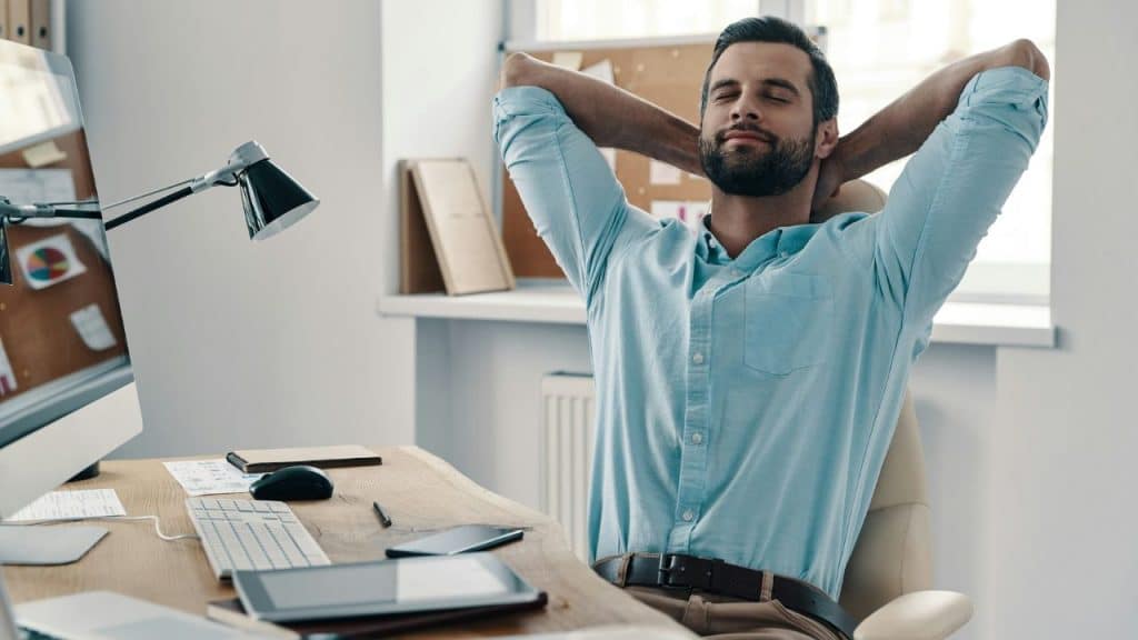 A relaxed businessman is leaning back in his chair with his eyes closed.