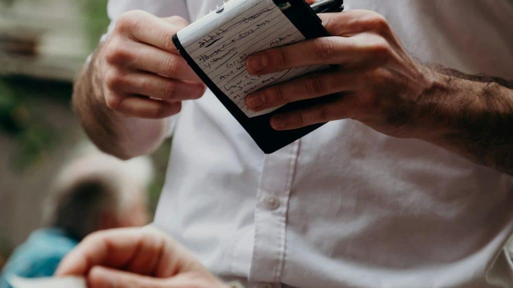 A waiter holding a notepad while taking an order.