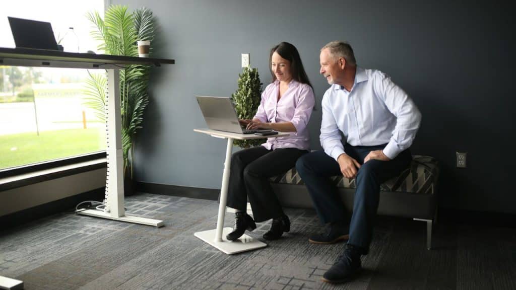 A mature businessman and woman are working together on a laptop in an office.