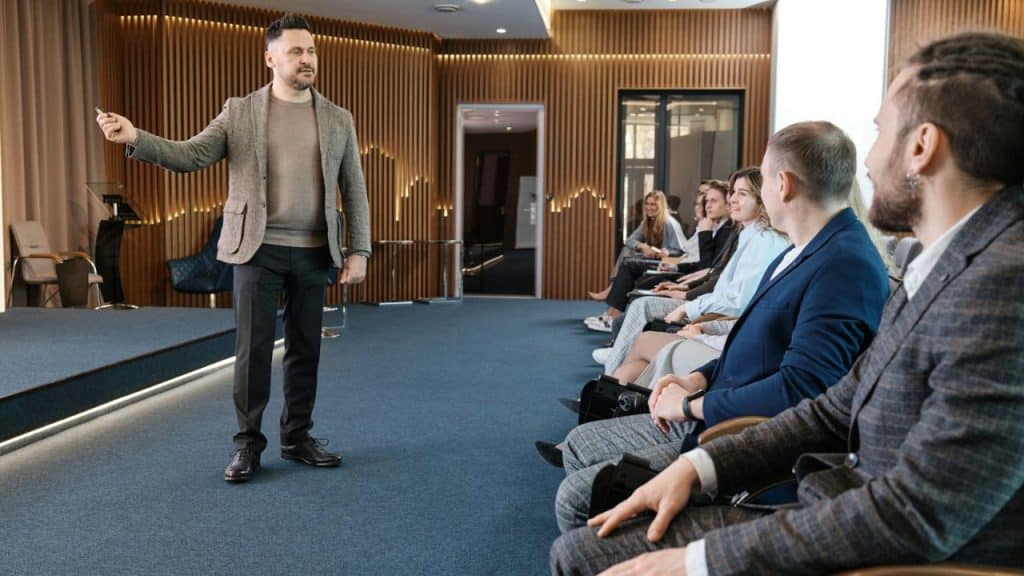 A man is giving a presentation to a seated audience in a modern conference room.