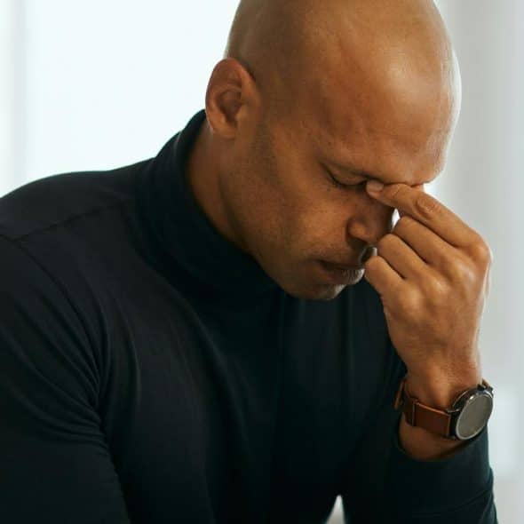 A man holding his face in apparent stress or fatigue.