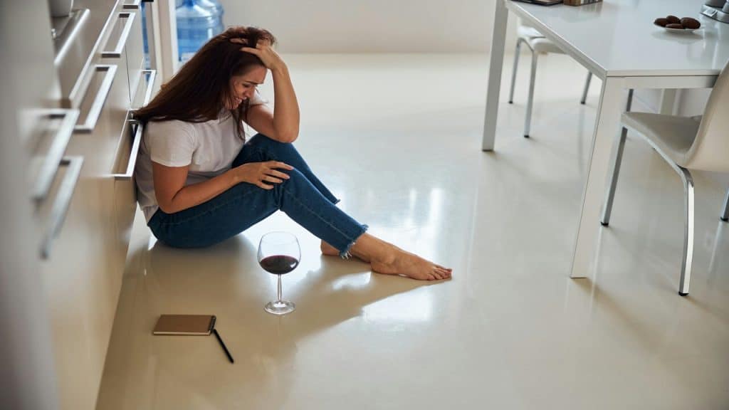 A woman drinking wine while upset
