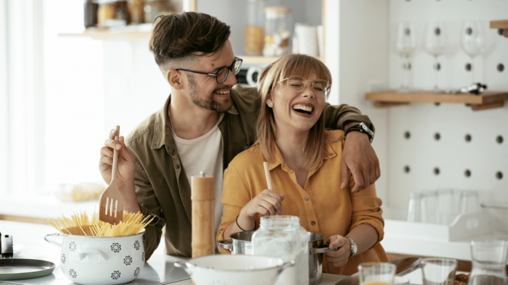 A couple laughing in the kitchen together