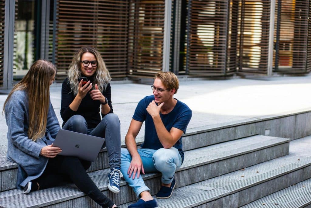 Women and a man sitting at the stairs