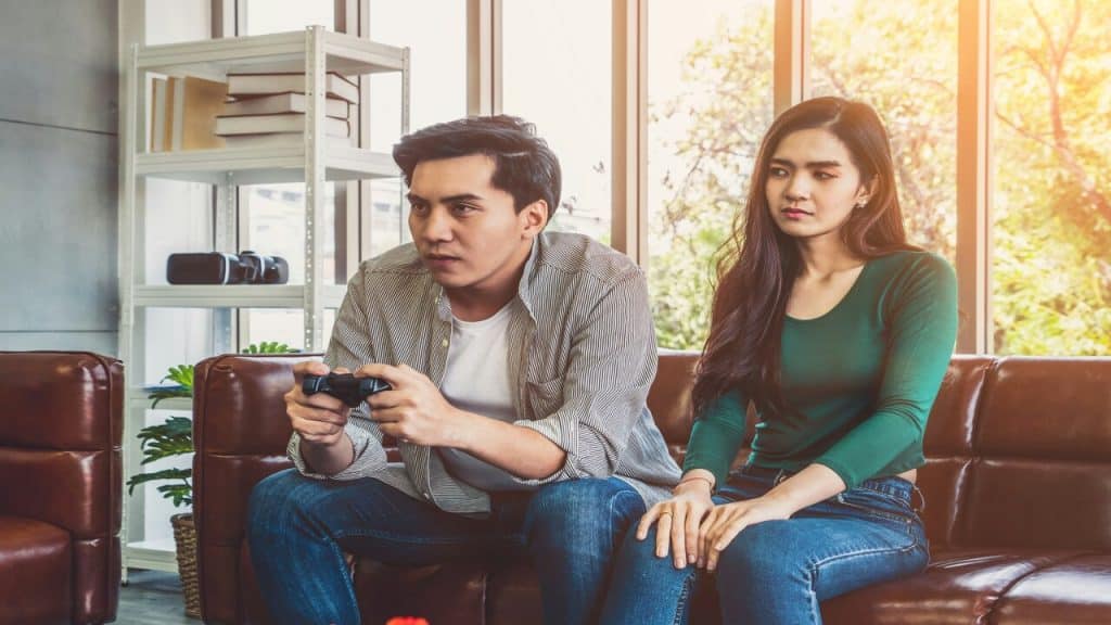 A man ignoring his wife while playing video games