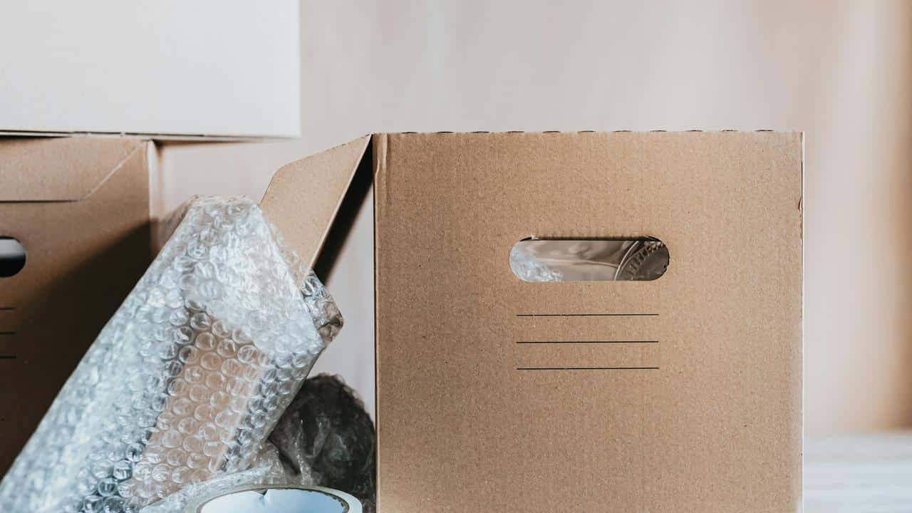 A cardboard box with bubble wrap and packing tape nearby.