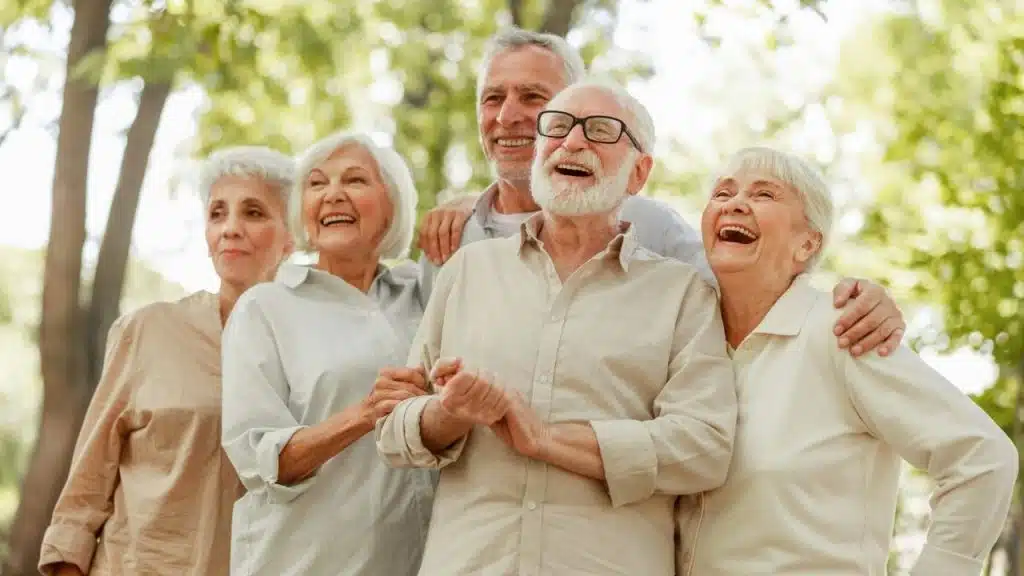 A diverse group of five joyful, elderly people laughing outdoors.