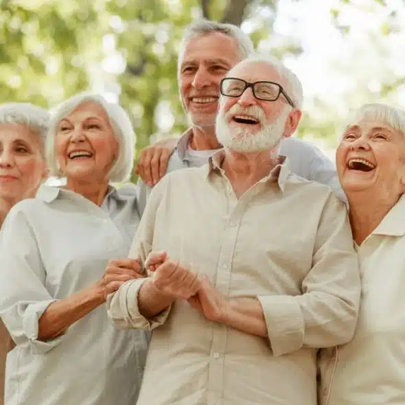 A diverse group of five joyful, elderly people laughing outdoors.