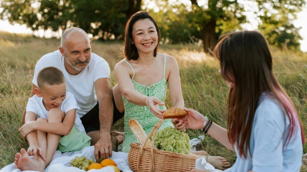 A diverse family enjoying a sunny picnic in a grassy park.