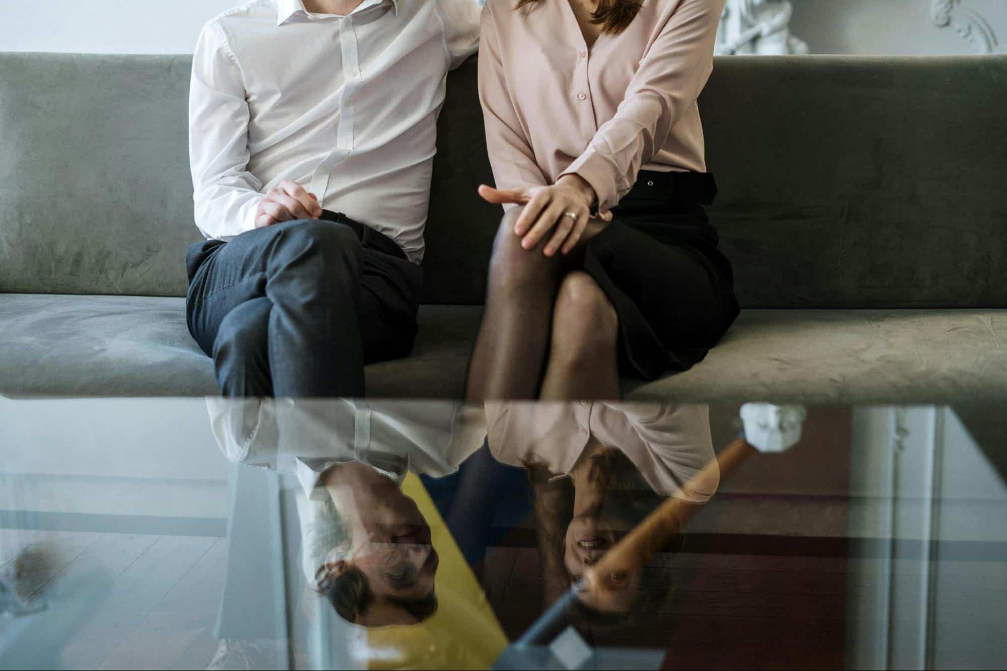 A married couple sitting at the couch and talking.