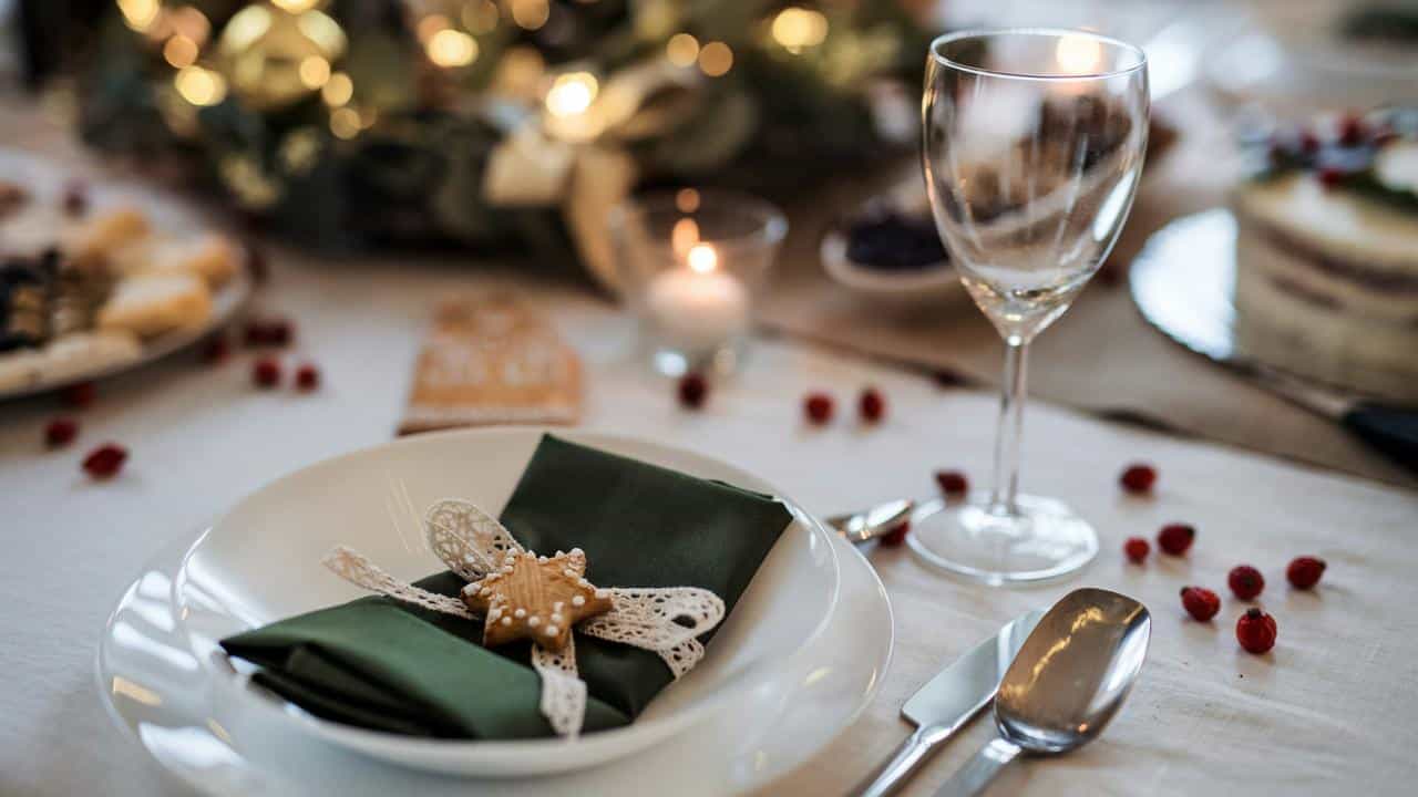 A festive dinner table set with candles, plates, and a decorated napkin.