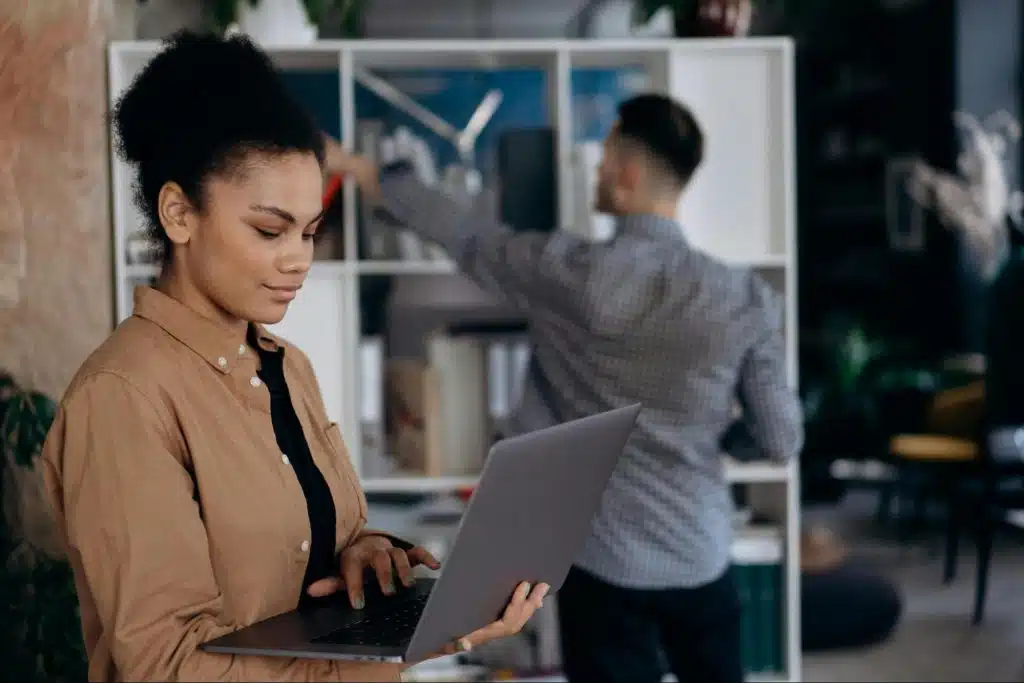 A woman holding a laptop near to a man
