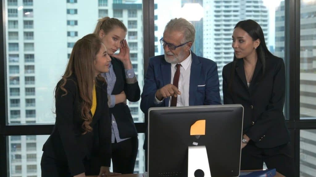 A diverse group of four business professionals looking at a computer screen.