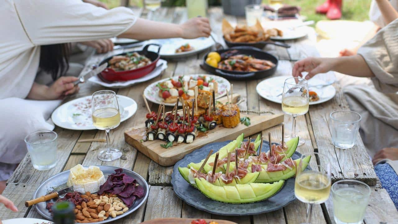 A group of people enjoying a meal with various dishes on a wooden table.