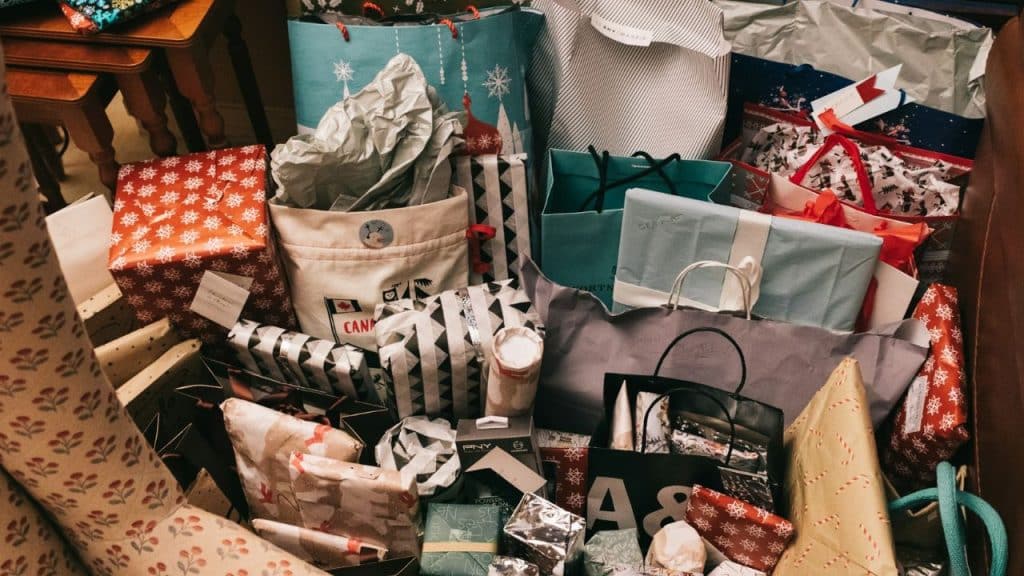 A chaotic pile of many wrapped presents and gift bags with paper.